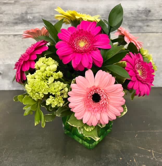 Bouquet of pink, peach, and yellow gerbera daisies in a green vase