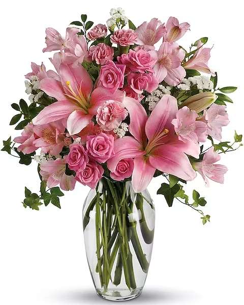 Pink lilies and roses arranged in a clear glass vase