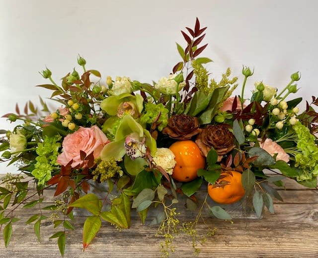wish i could be there centerpiece - a textural, seasonal table centerpiece in soft peach, green, white with fall leaves. this centerpiece includes seasonal fruit, cymbidium, hydrangea and fall leaves