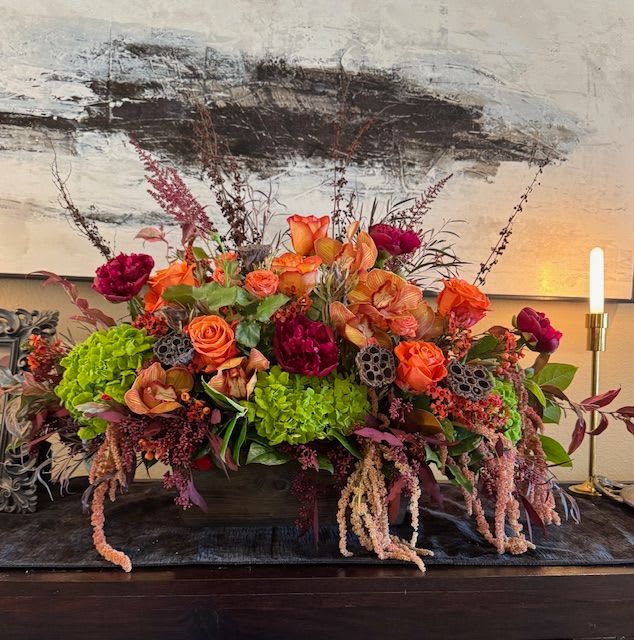 Large floral centerpiece with orange and magenta blooms in a low container