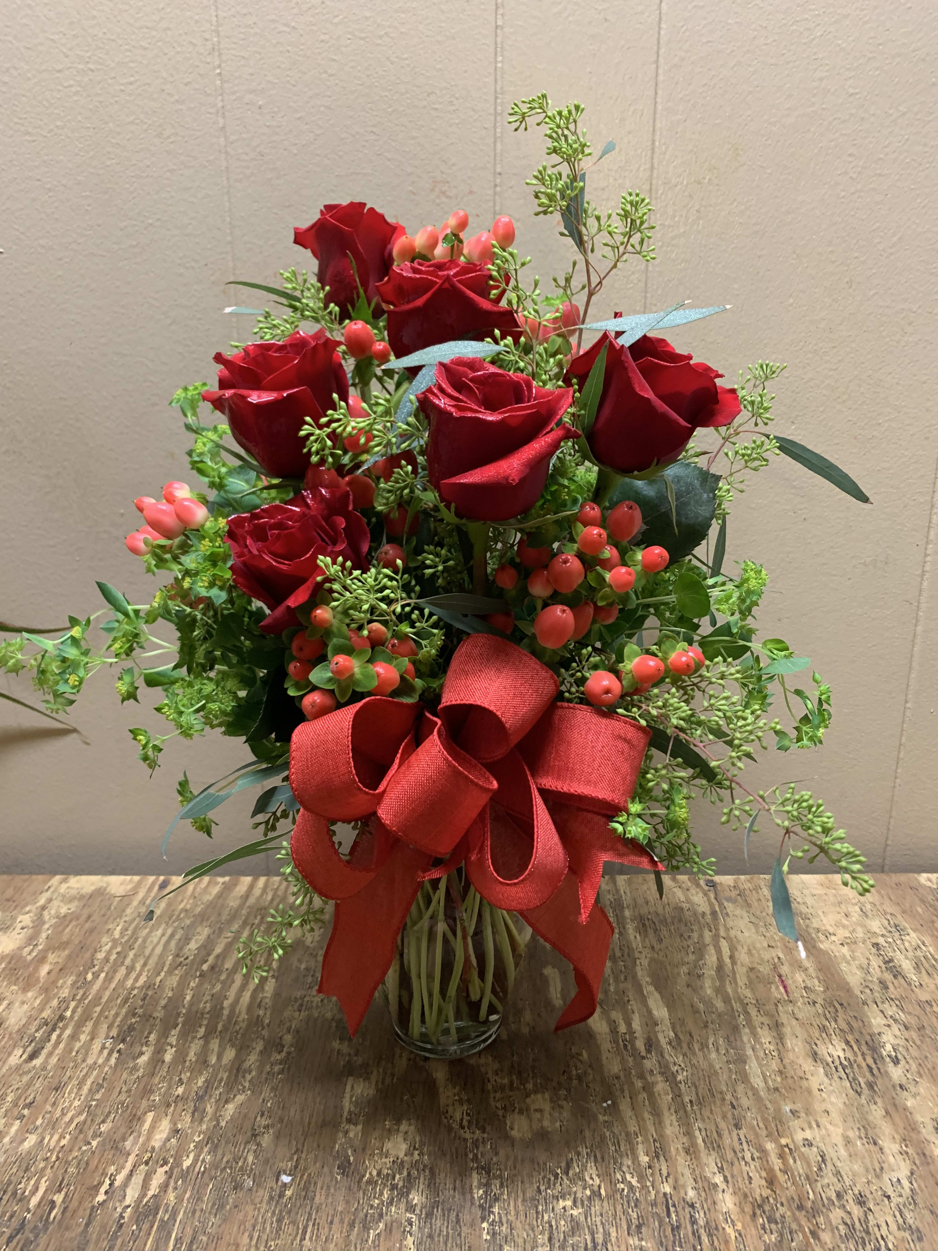 Red roses in a glass vase with a large red ribbon