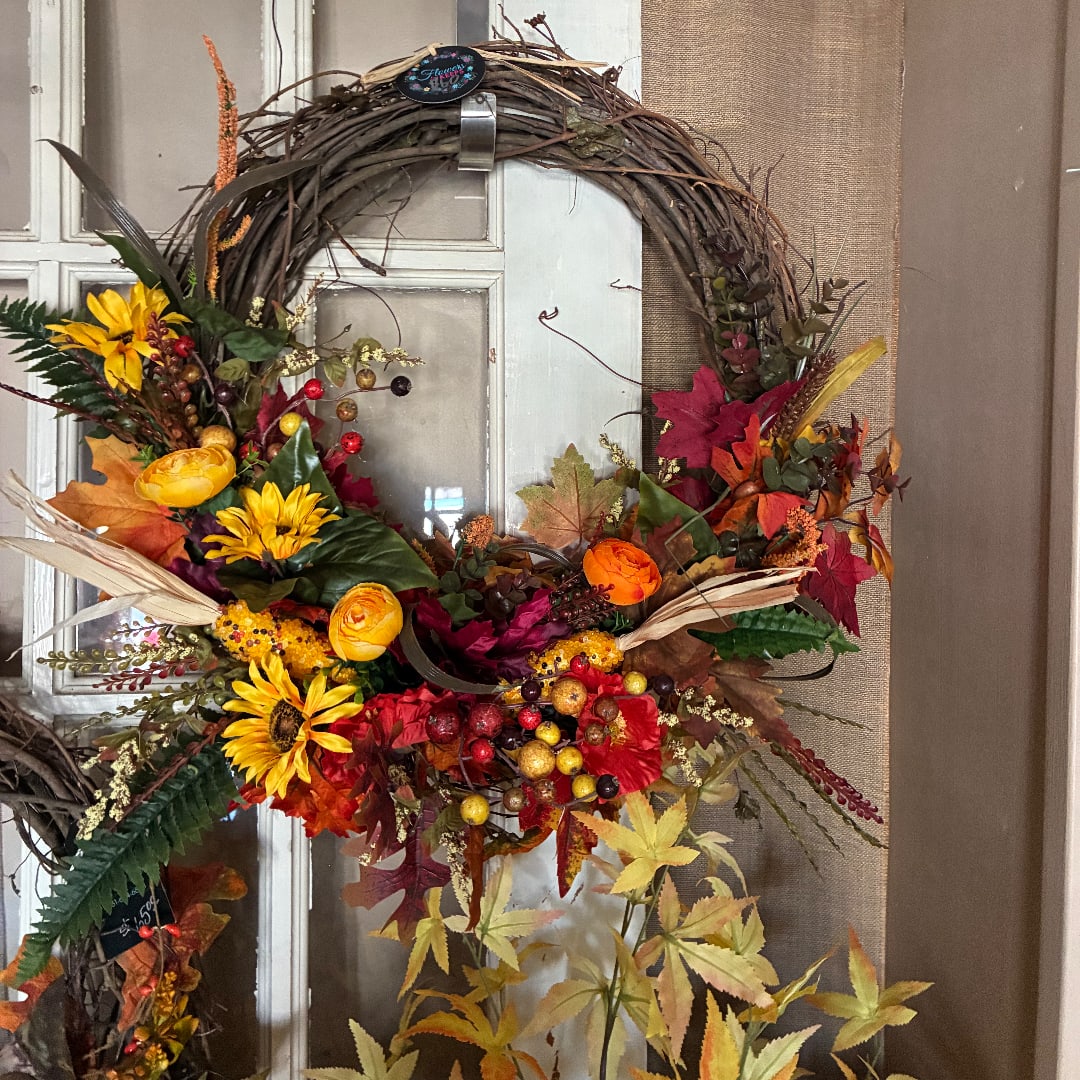 Autumn wreath with yellow and orange flowers on a twig base