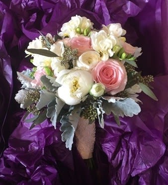 Bouquet of pink and white flowers wrapped in purple paper