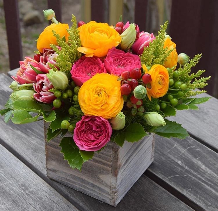 Bright mixed bouquet in a wooden box with yellow and pink blooms