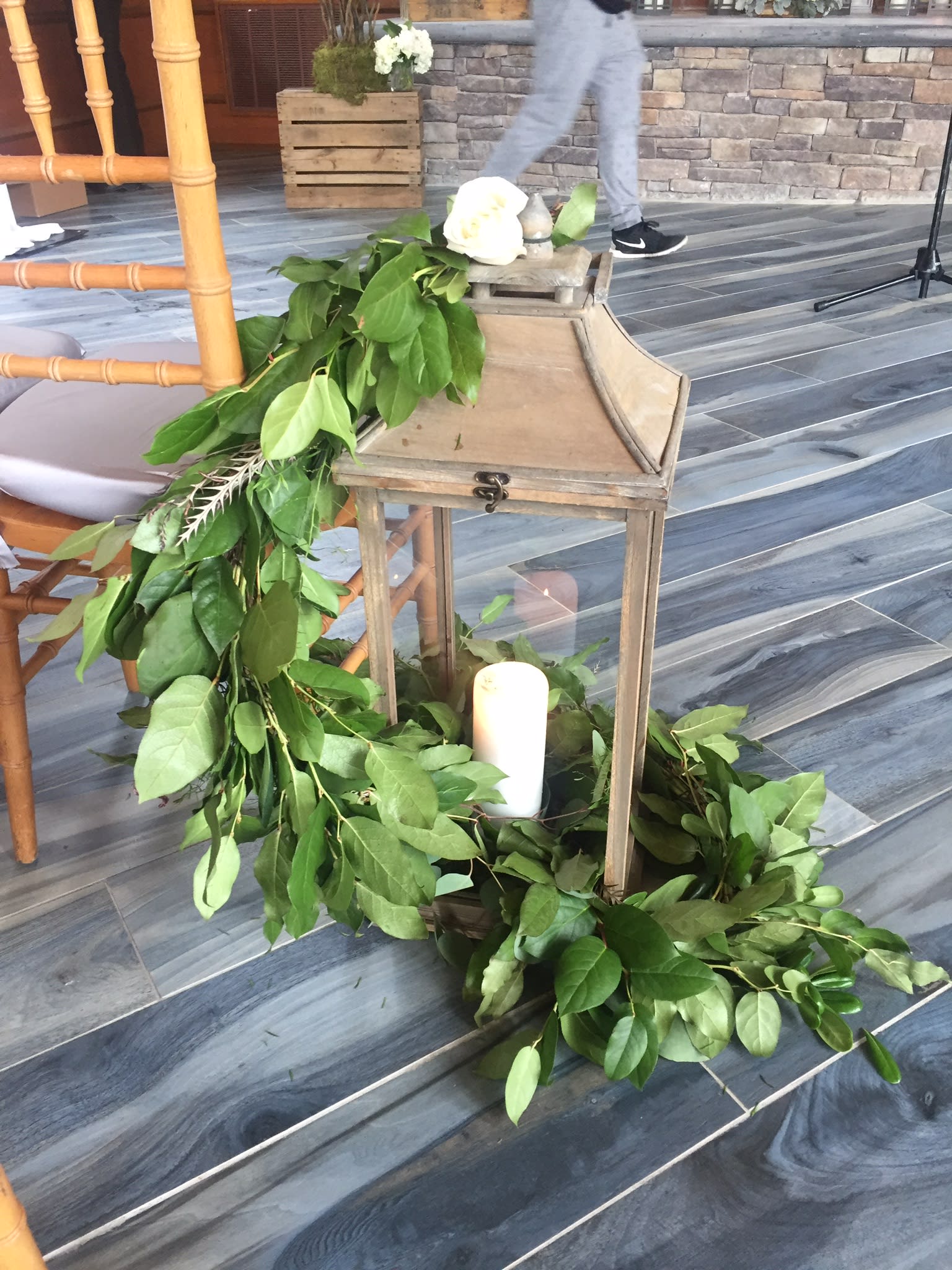 Green garland draped around a wooden lantern with white candles