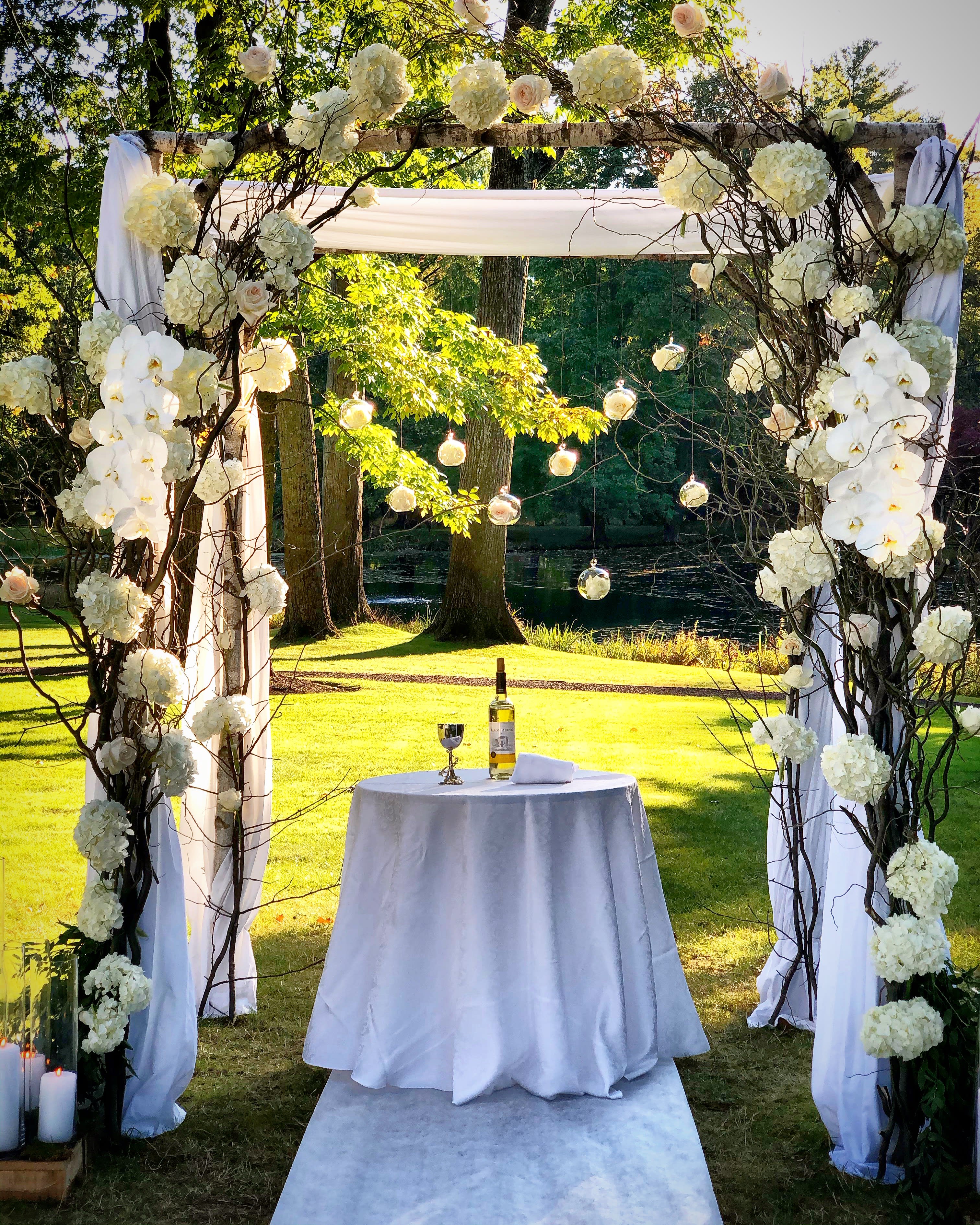 Birch Chuppah Artistically Arranged - Birch Chuppah Artistically Arranged is truly an expression of love. Birch tree based, this Chuppah is embellished with curly willow, pure white hydrangea and cascading floating glass orbs filled with garden roses. 