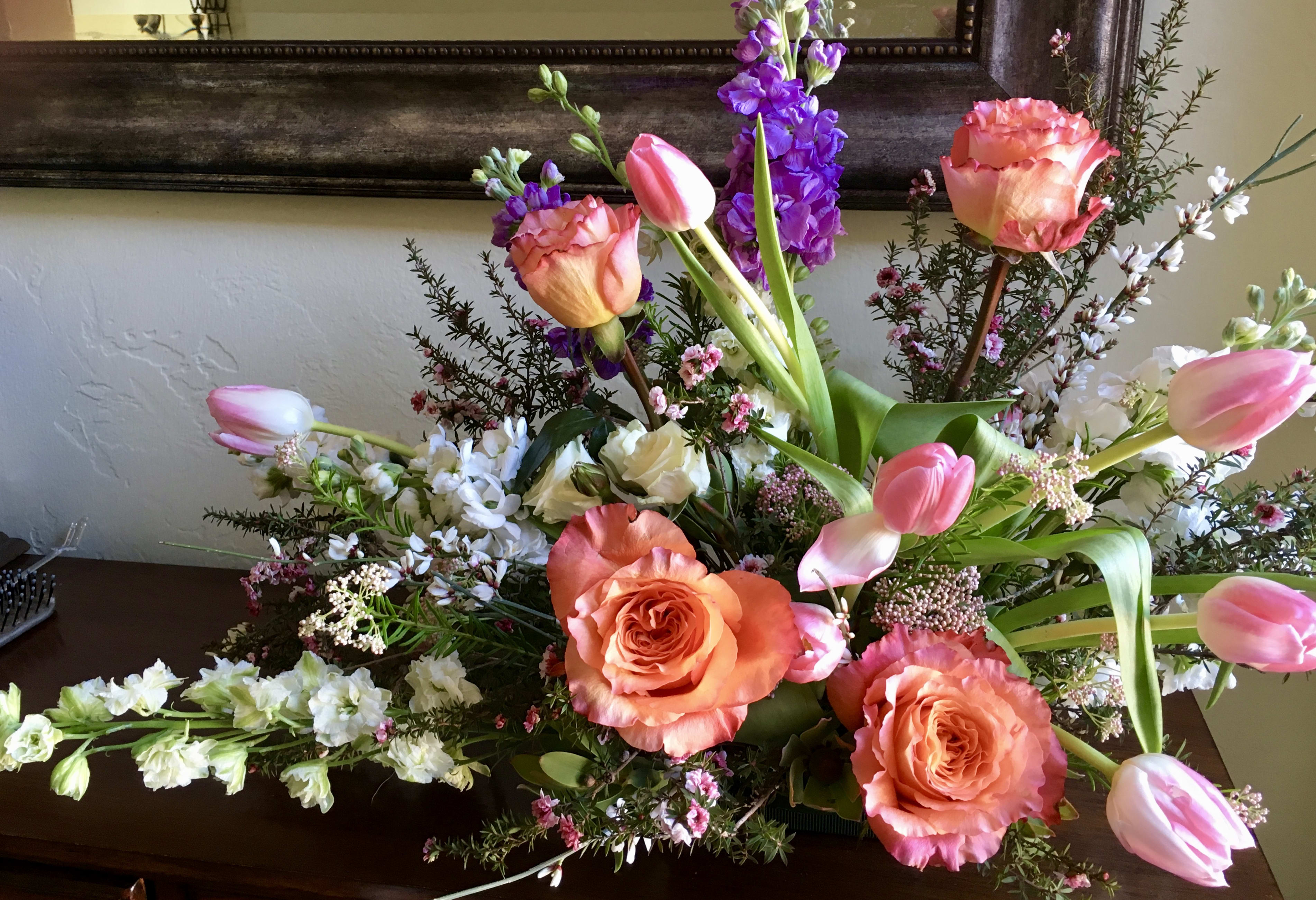 Let Spring Ring In - Welcome spring into your home with this gorgeous conversation piece, great for an entry way table.  This arrangements is filled with peach to pink tulips, pink to peach garden roses, spring time branches along with touches of purple stock.