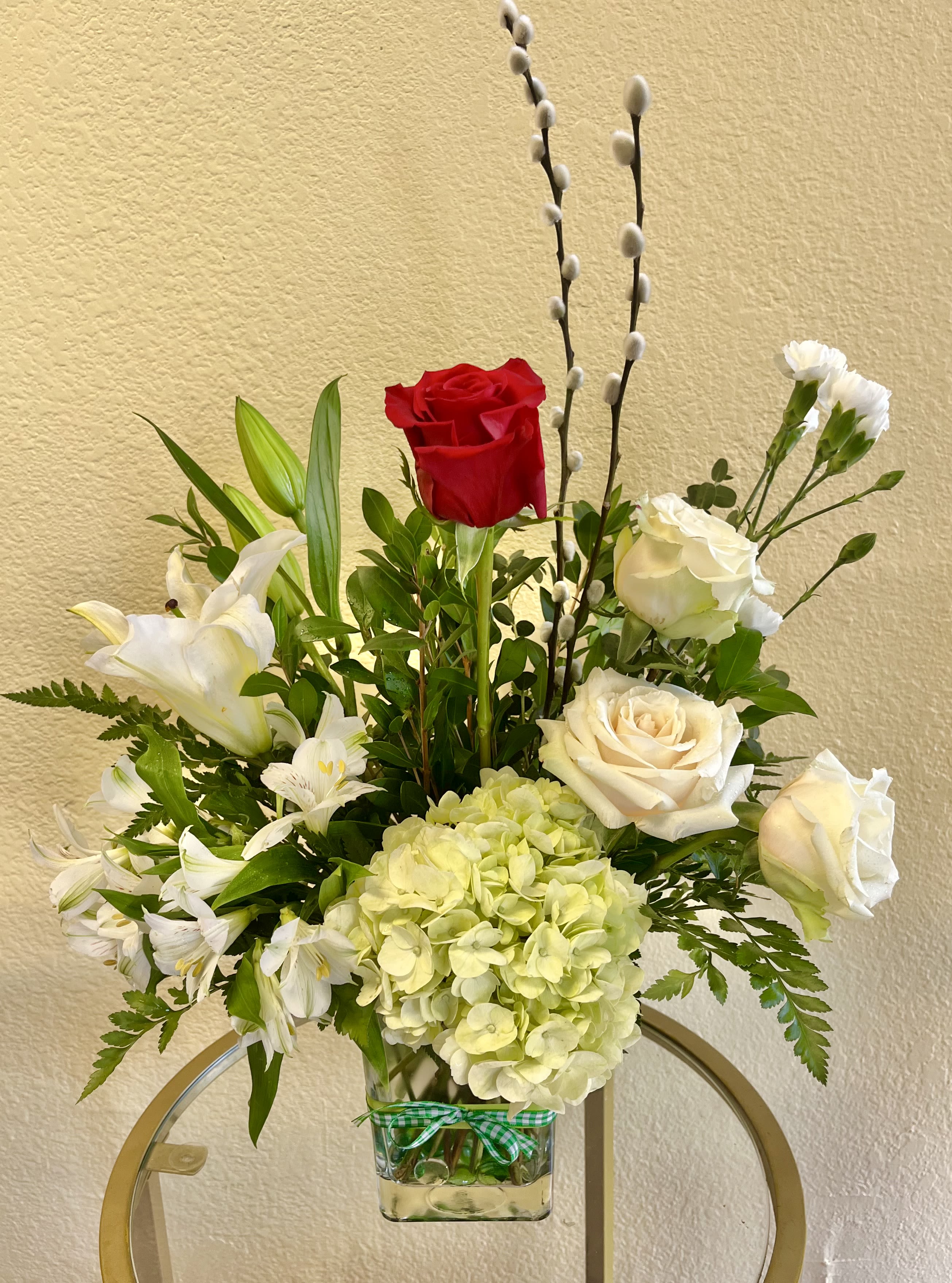 Mixed bouquet with red and white roses, lilies, and pale hydrangea in a glass vase