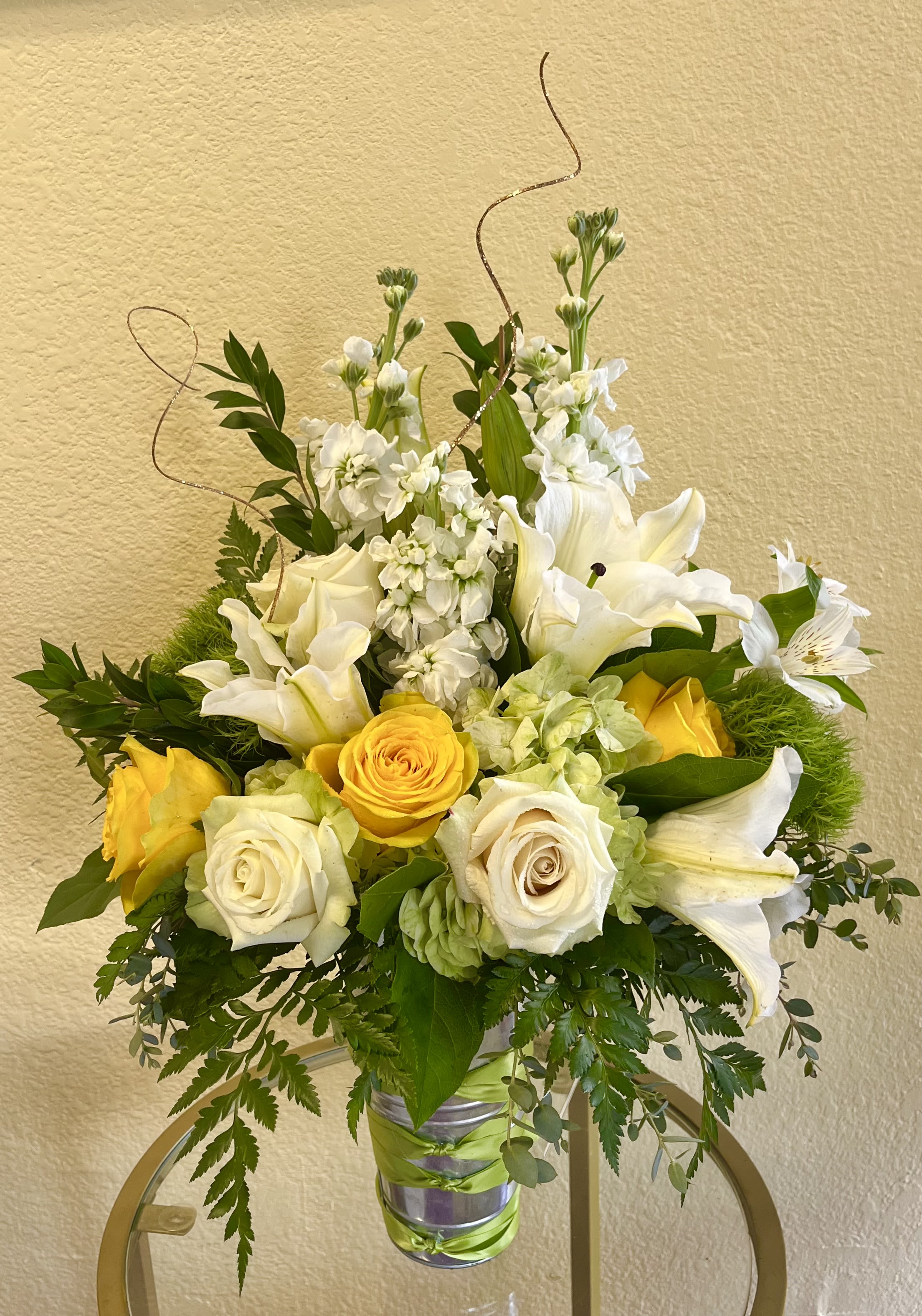 Yellow and white floral arrangement in a silver vase