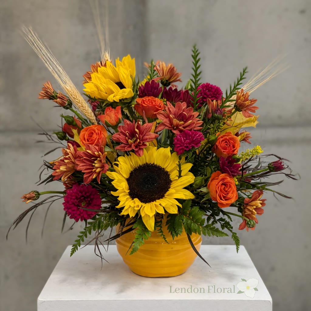 Sunflower and orange flower arrangement in a yellow vase