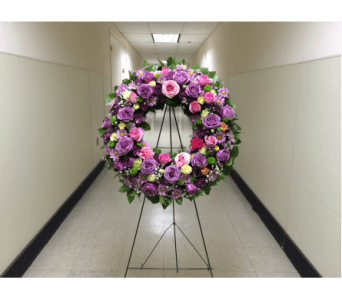Large circular floral wreath on a metal stand with pink and purple roses