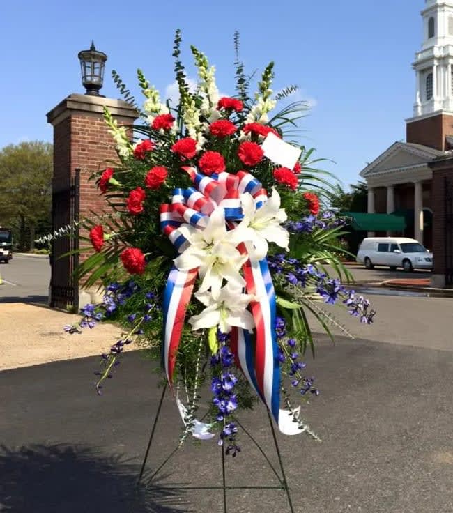 Large standing floral spray with red, white, and blue flowers and ribbon