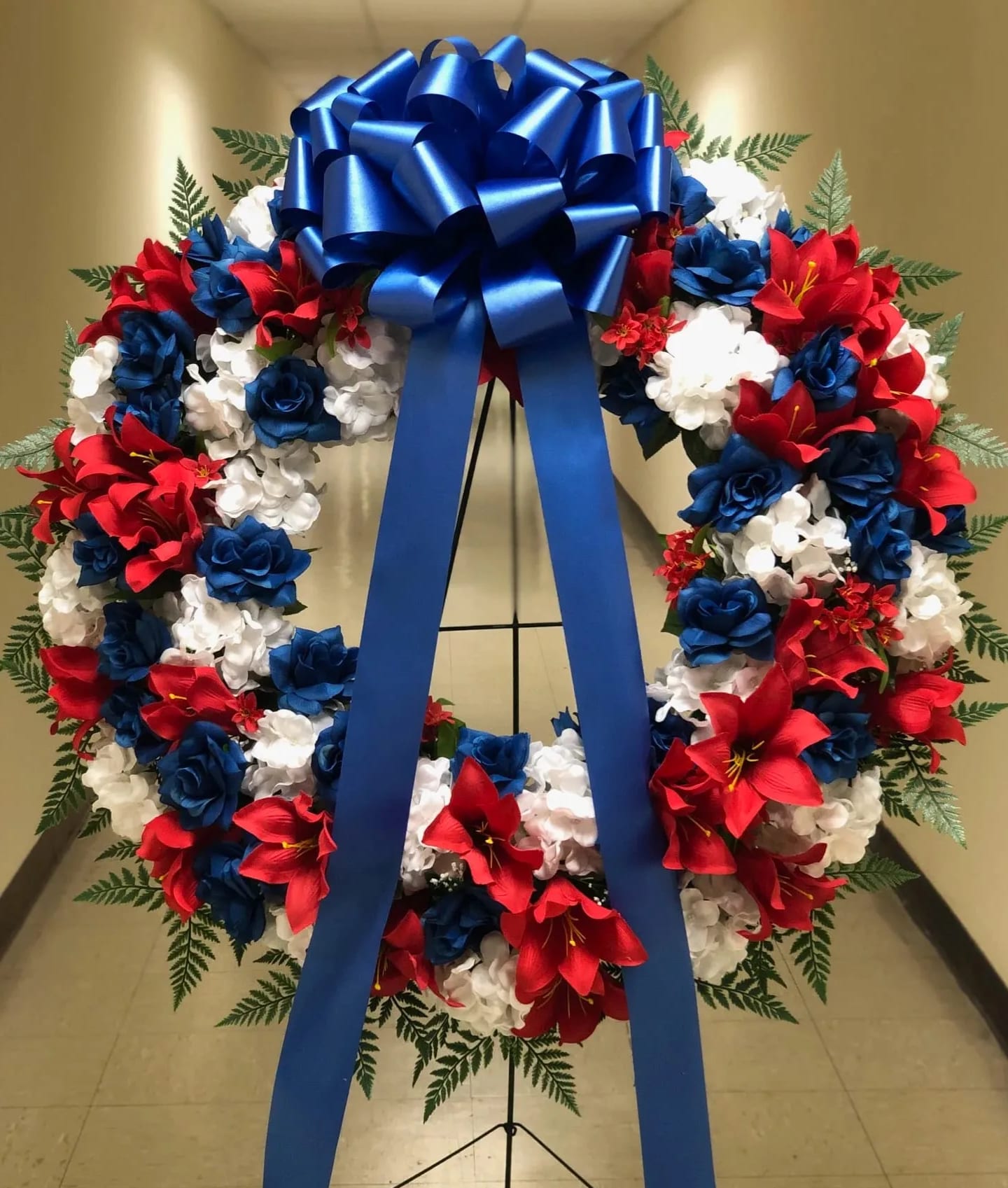 Red, white, and blue floral wreath with a large blue bow