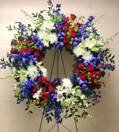 Large circular wreath of red, white, blue, and purple flowers on a stand
