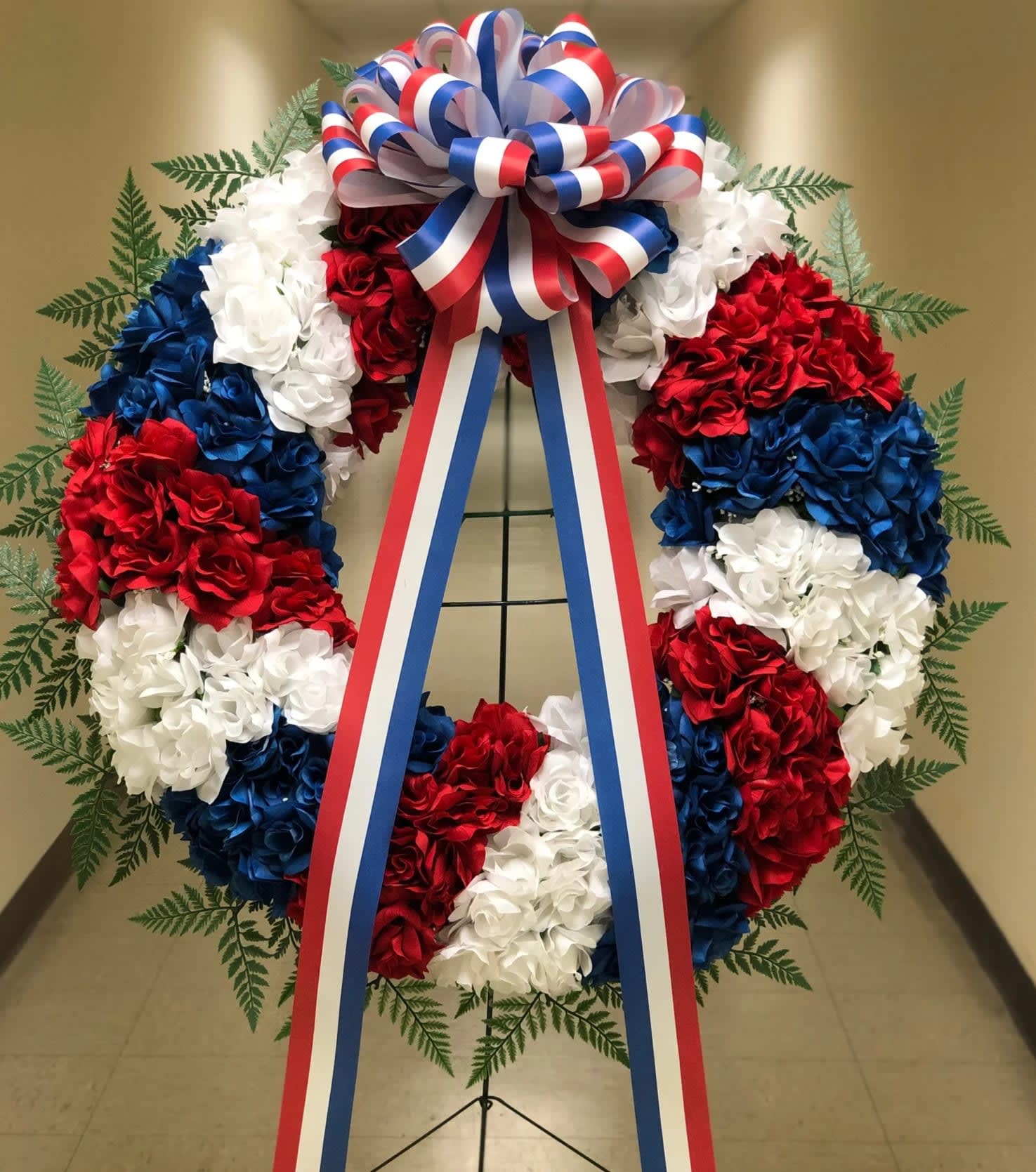 Red, white, and blue floral wreath with a patriotic ribbon bow
