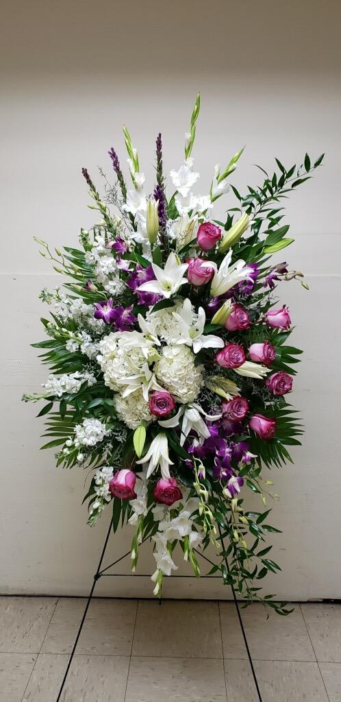 Tall standing floral spray with white lilies, pink roses, and purple orchids