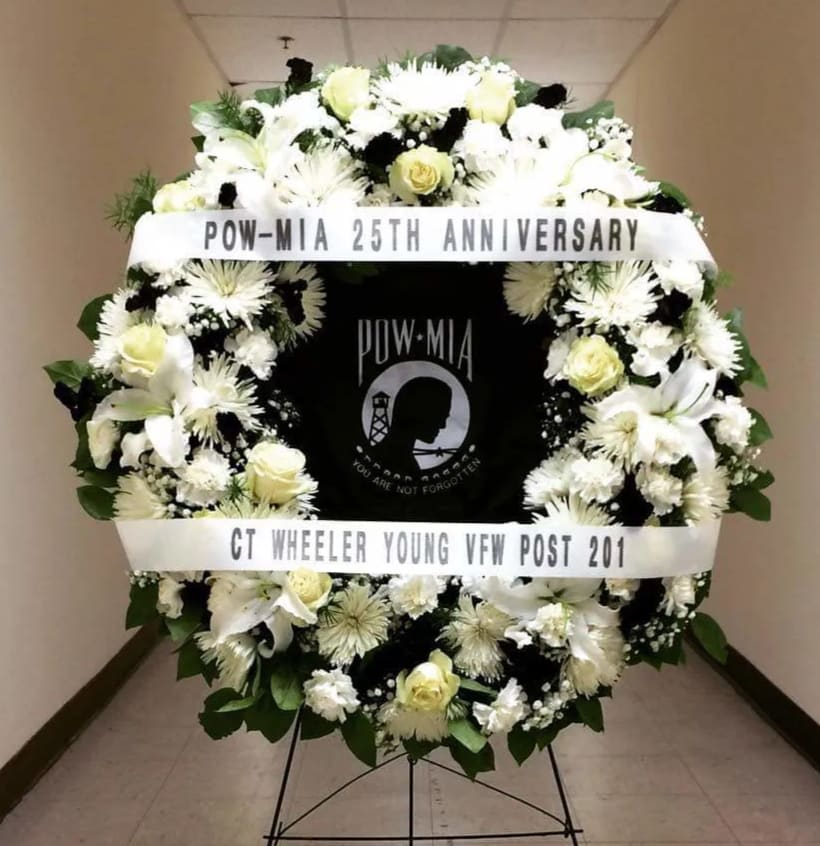 White funeral wreath with ribbons and a POW-MIA tribute center