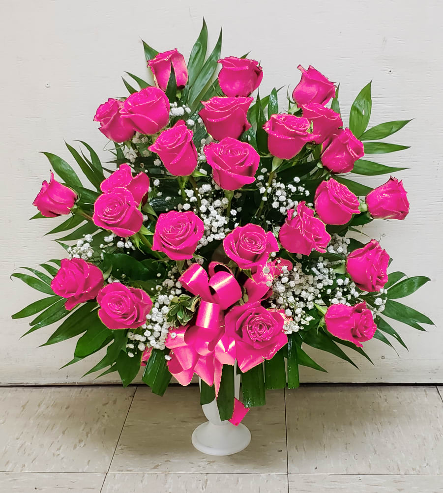 Bright pink roses in a white vase with baby's breath and greenery