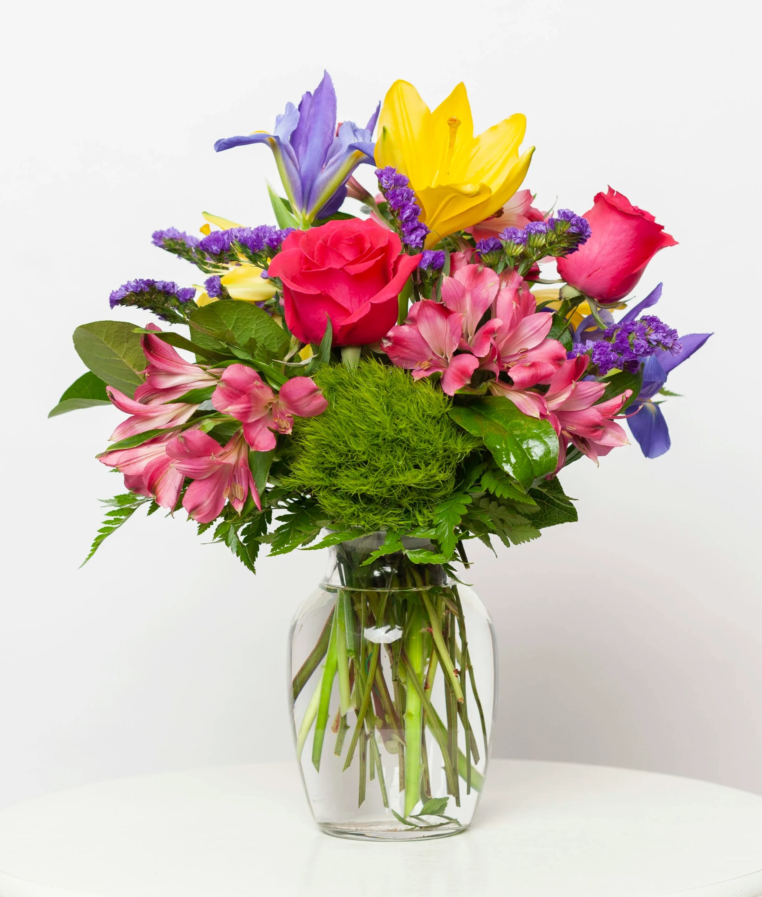 Colorful bouquet of roses, lilies, and alstroemeria in a clear glass vase