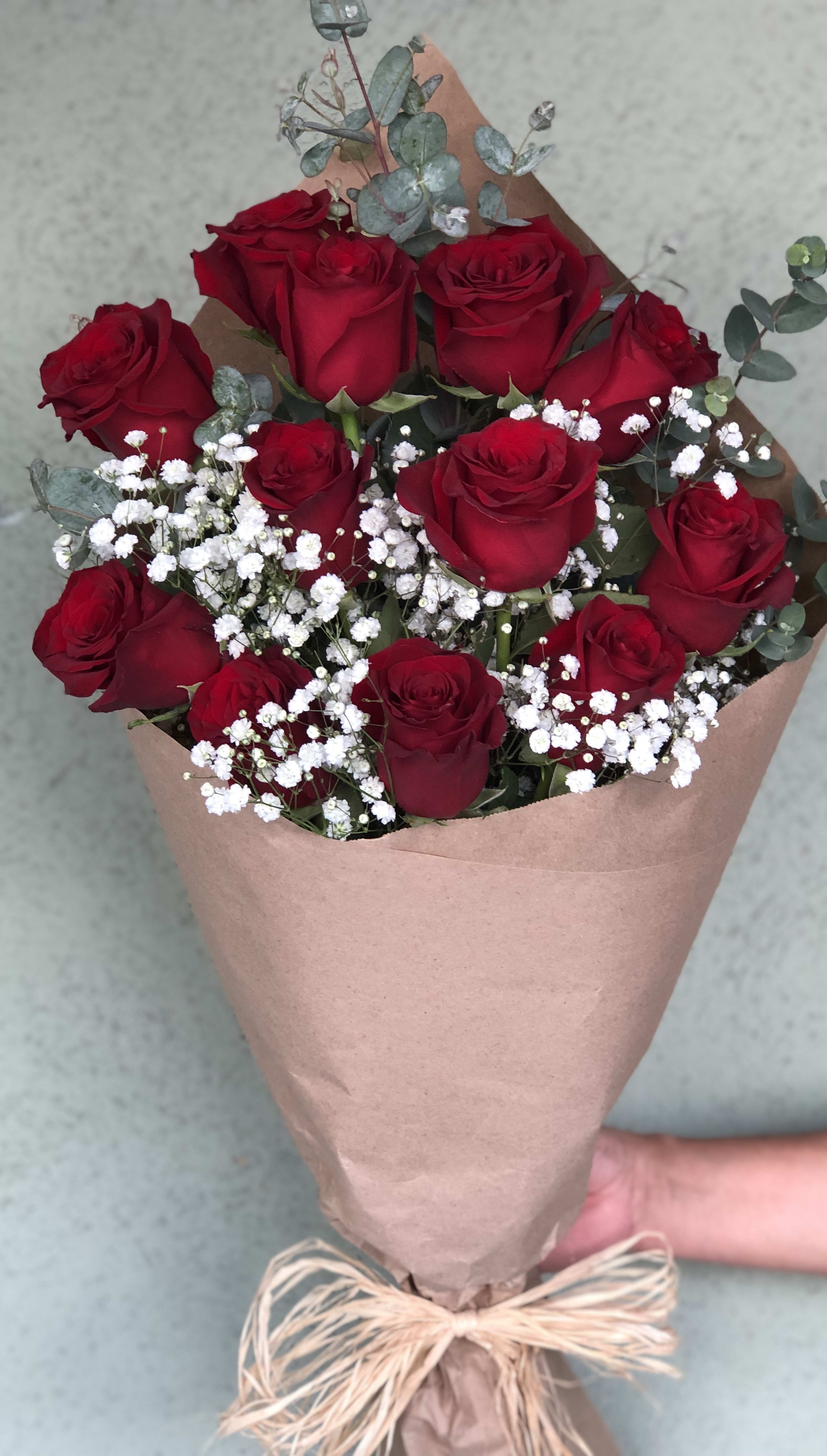 Bouquet of red roses with white baby's breath in brown paper