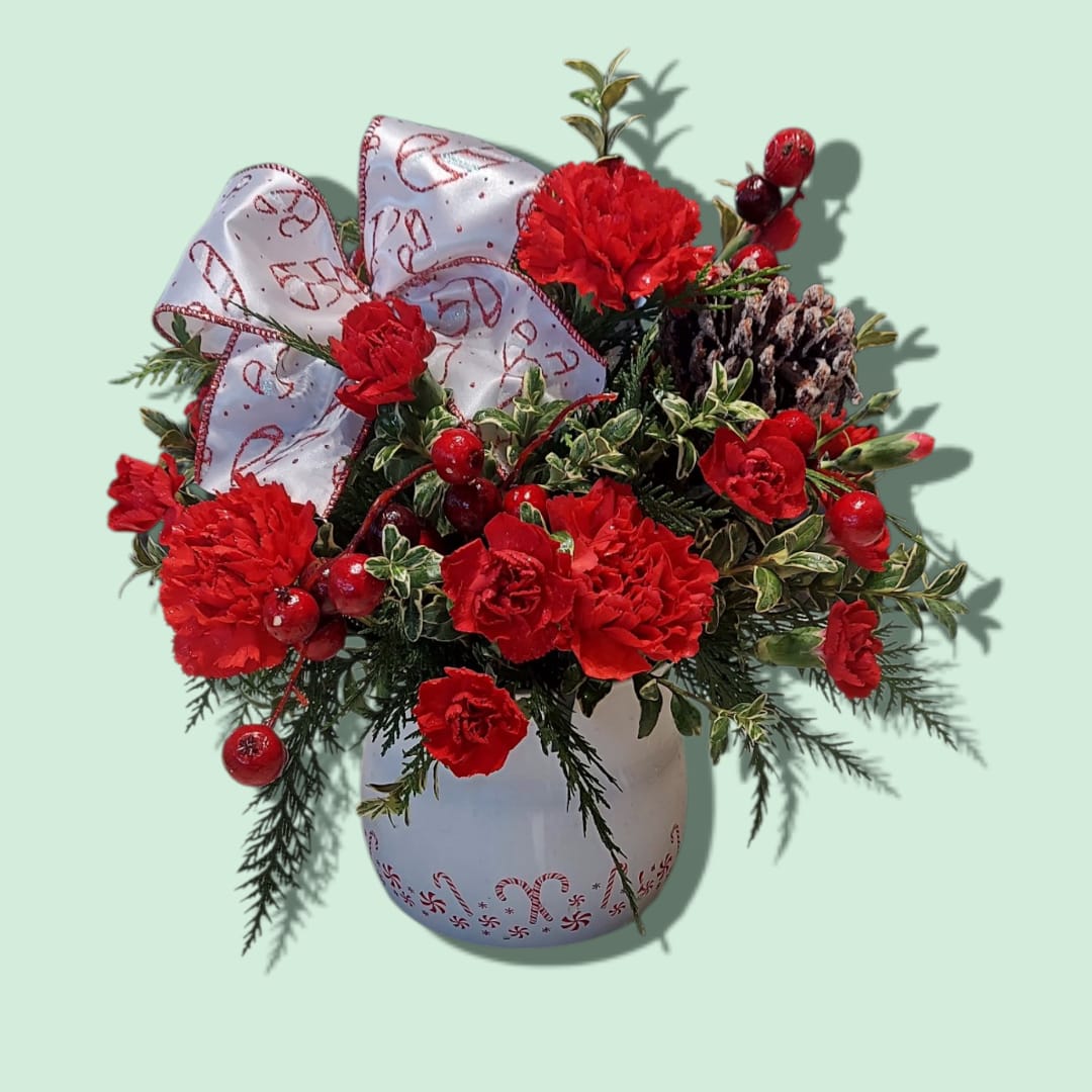 Red carnation arrangement in a white vase with a large ribbon bow