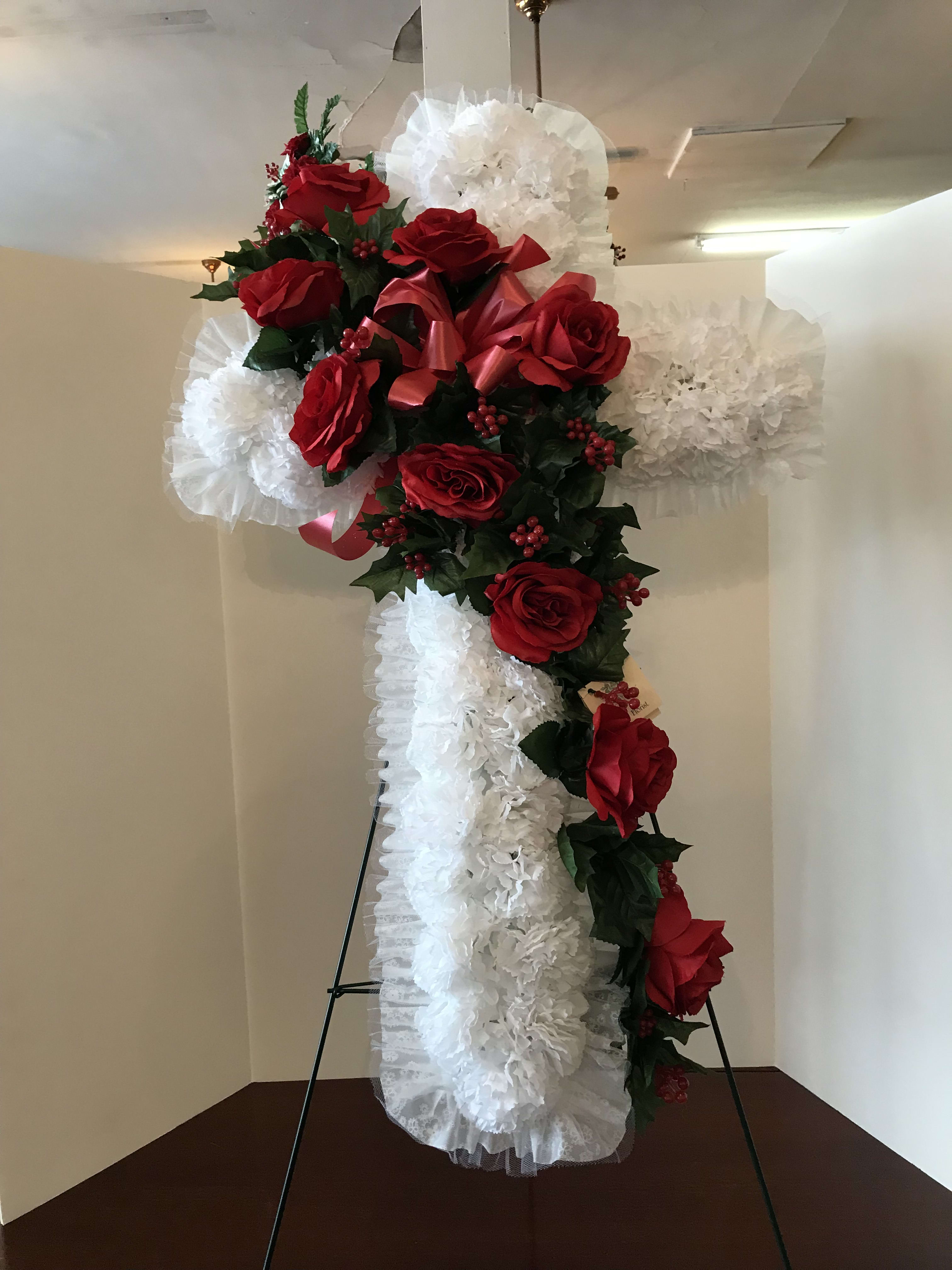Standing cross covered with red roses and white ruffled flowers