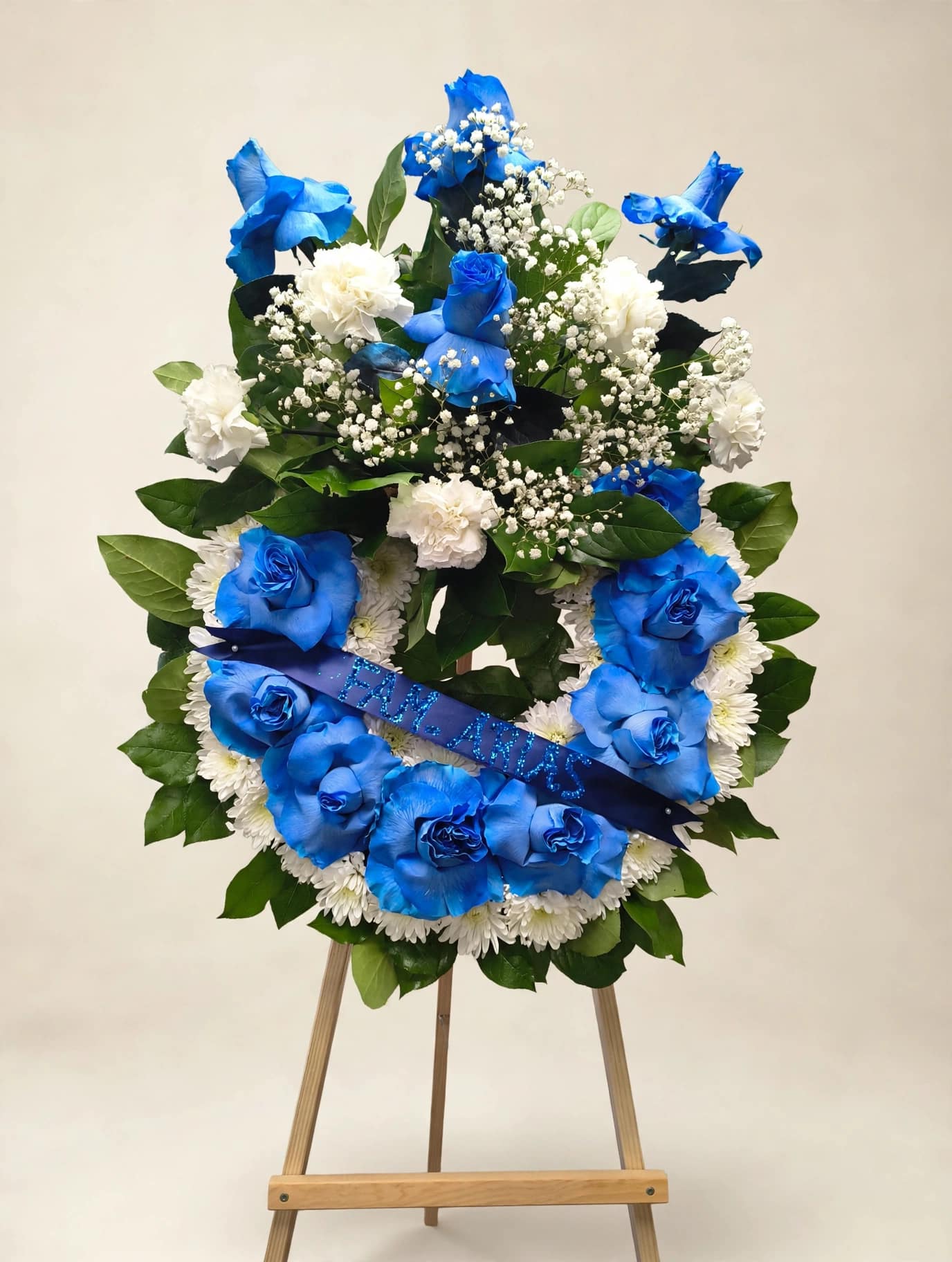 Blue and white floral wreath on an easel with a ribbon