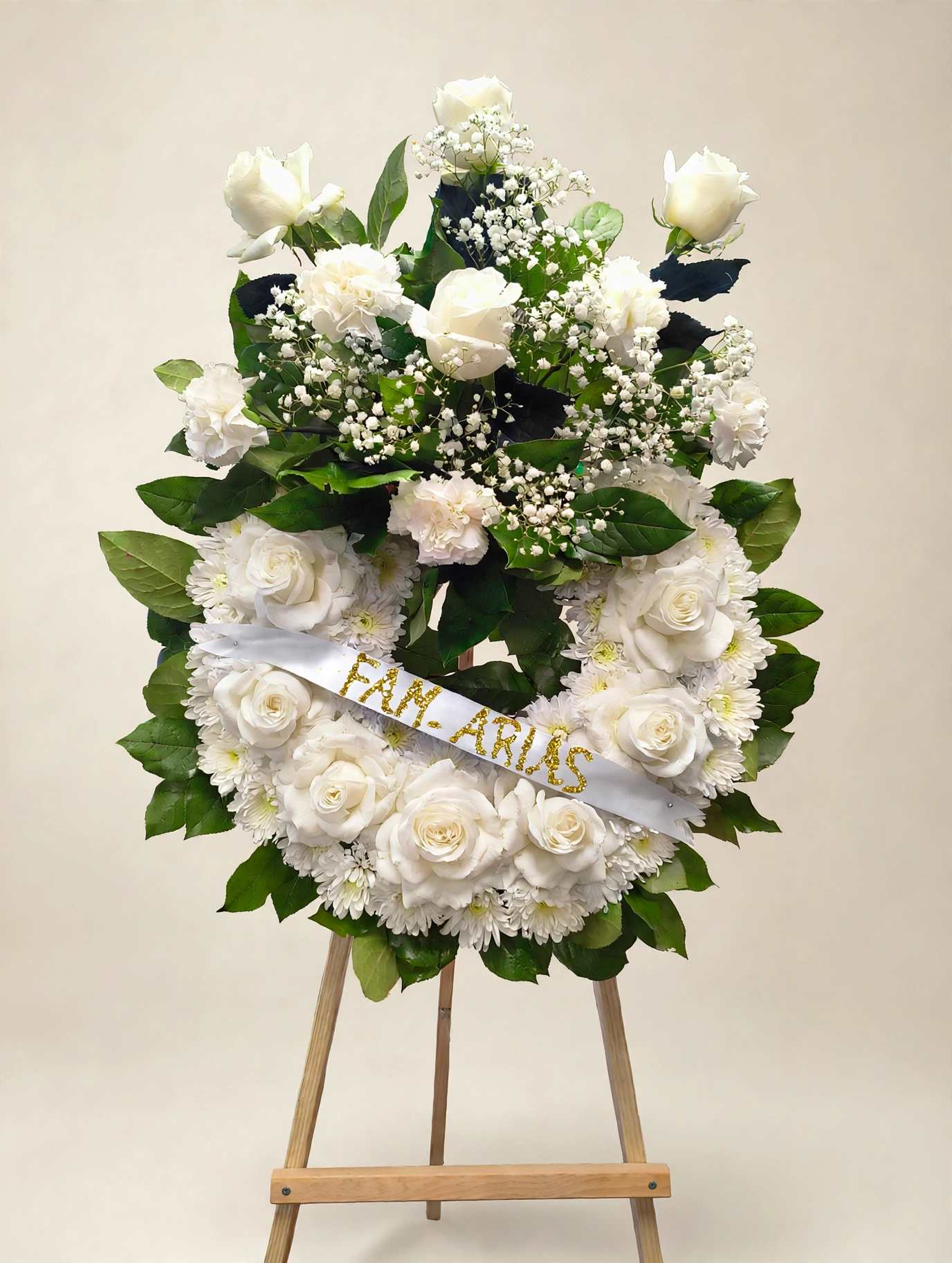 White rose and chrysanthemum wreath on an easel with a ribbon