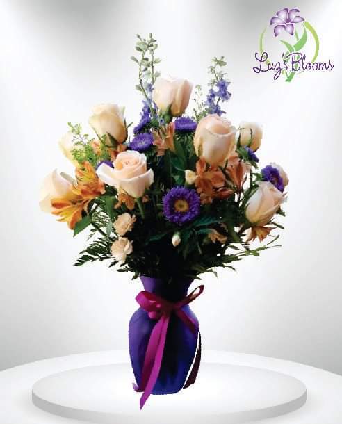 Bouquet of pale roses and purple flowers in a purple vase with ribbon