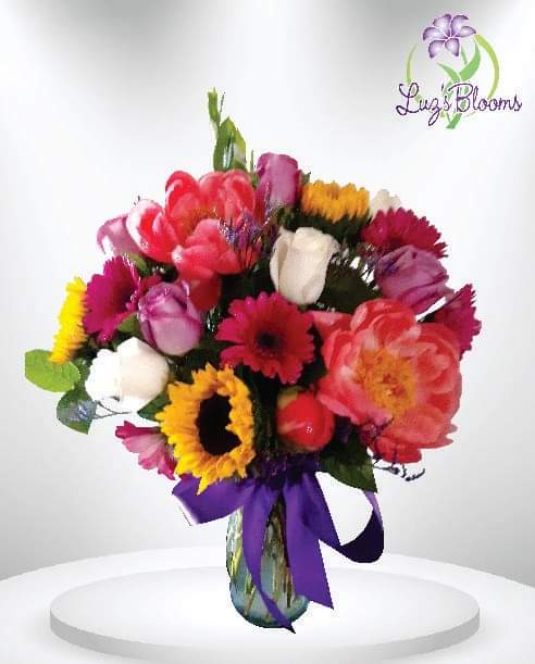 Colorful mixed bouquet in a glass vase with a purple ribbon