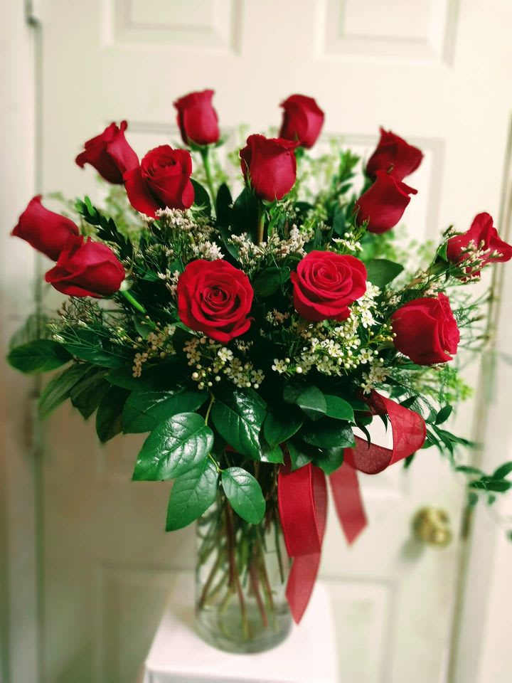 Bouquet of red roses in a clear glass vase with a red ribbon