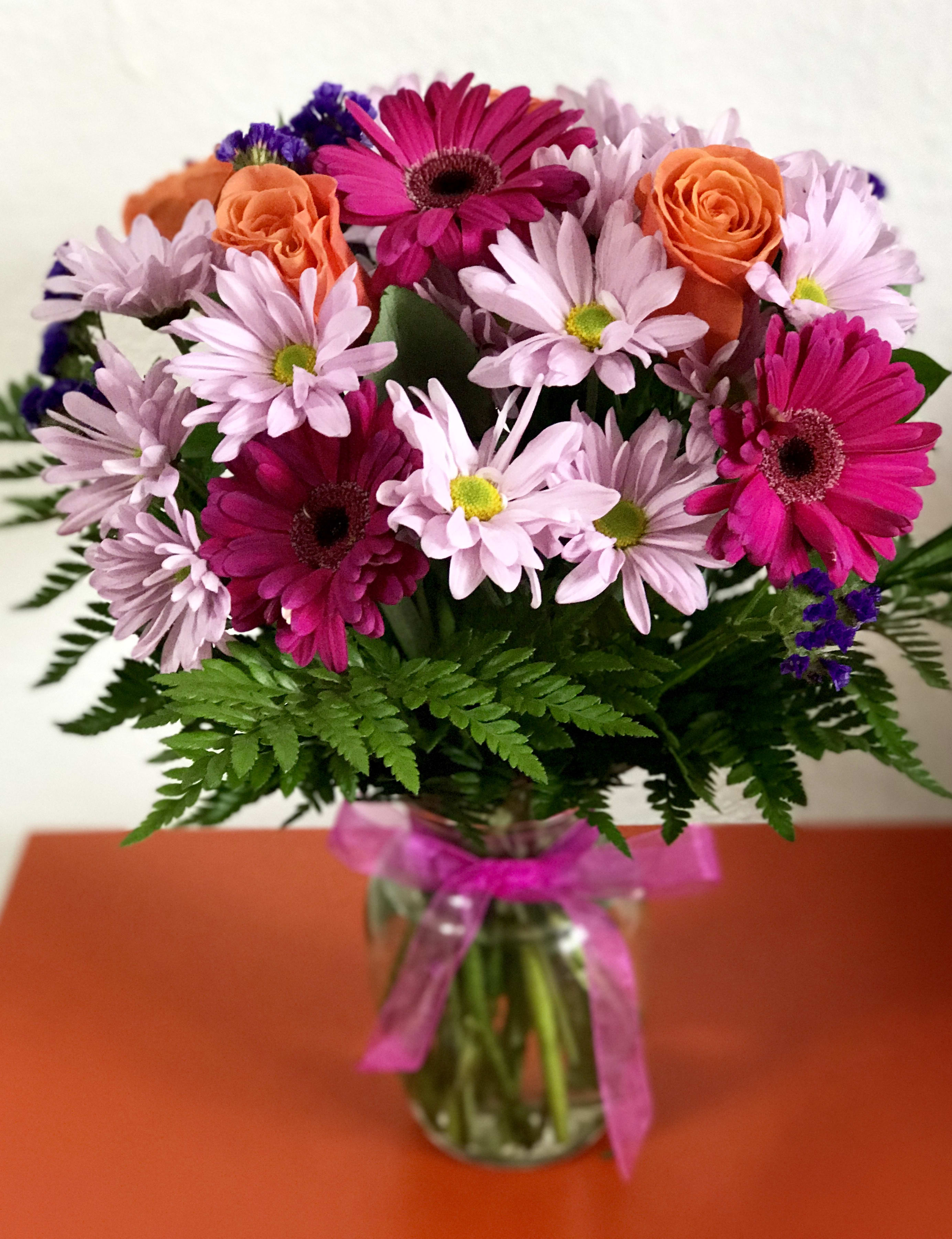 Bouquet of pink daisies and orange roses in a glass vase