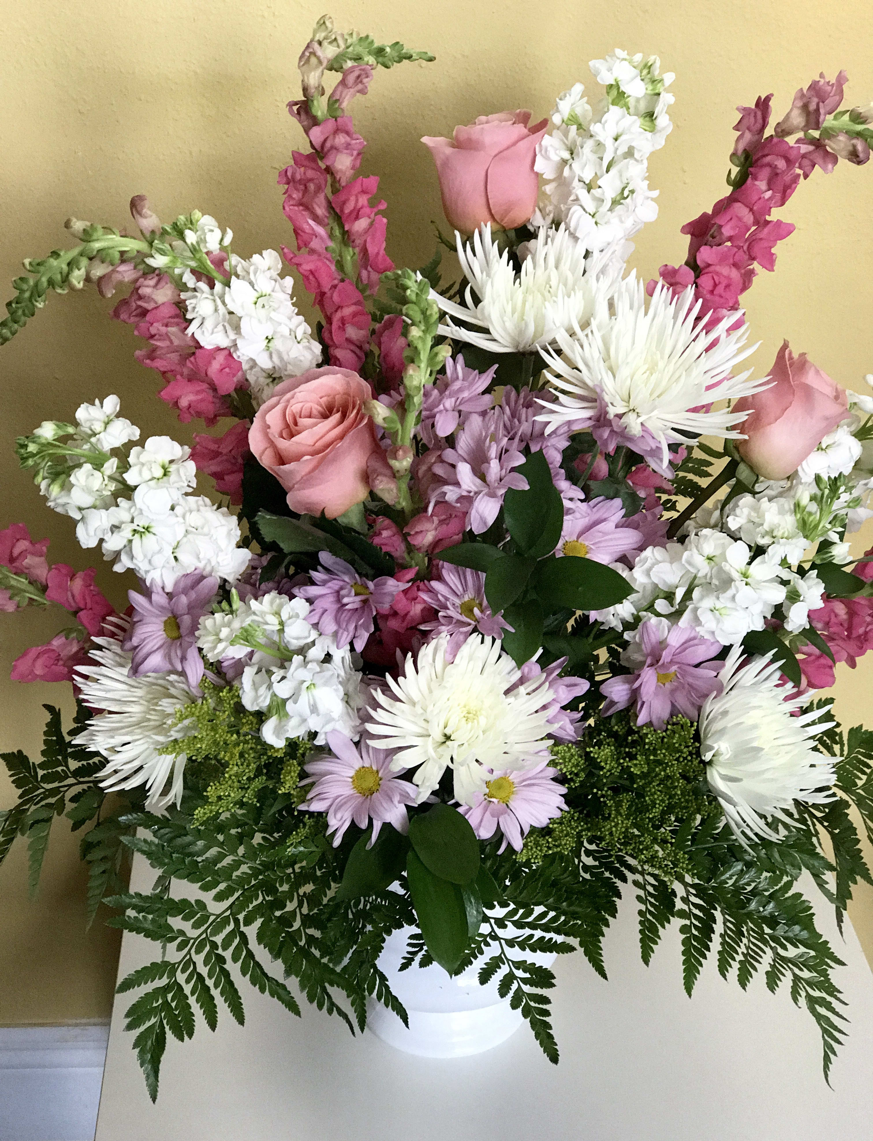 Mixed bouquet of pink roses, white chrysanthemums, and lavender daisies in a white vase