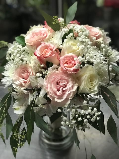 Bouquet of pink and white roses with baby's breath in a glass vase