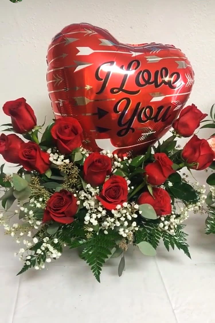 Red roses arranged around a heart balloon that says I Love You.