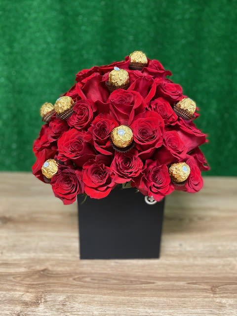Dome of red roses with gold-wrapped chocolates arranged in a black square box