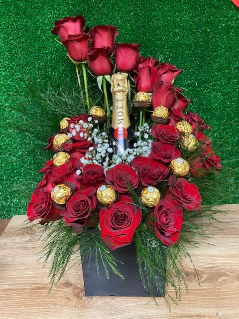 Red roses arranged around a champagne bottle with chocolates