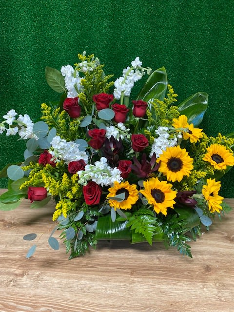 Red roses and yellow sunflowers in a low floral arrangement