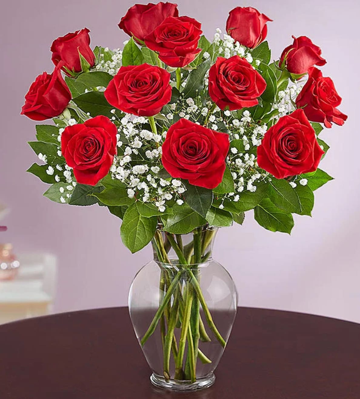 Arrangement of red roses with white filler flowers in a clear glass vase