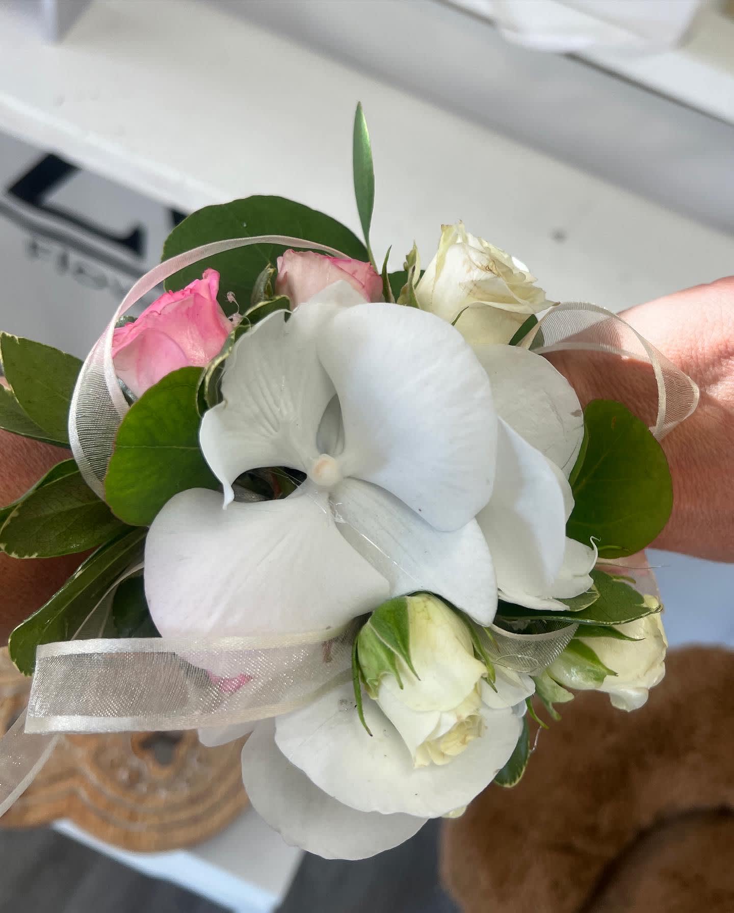 Small bouquet with white orchids and pink roses tied with sheer ribbon