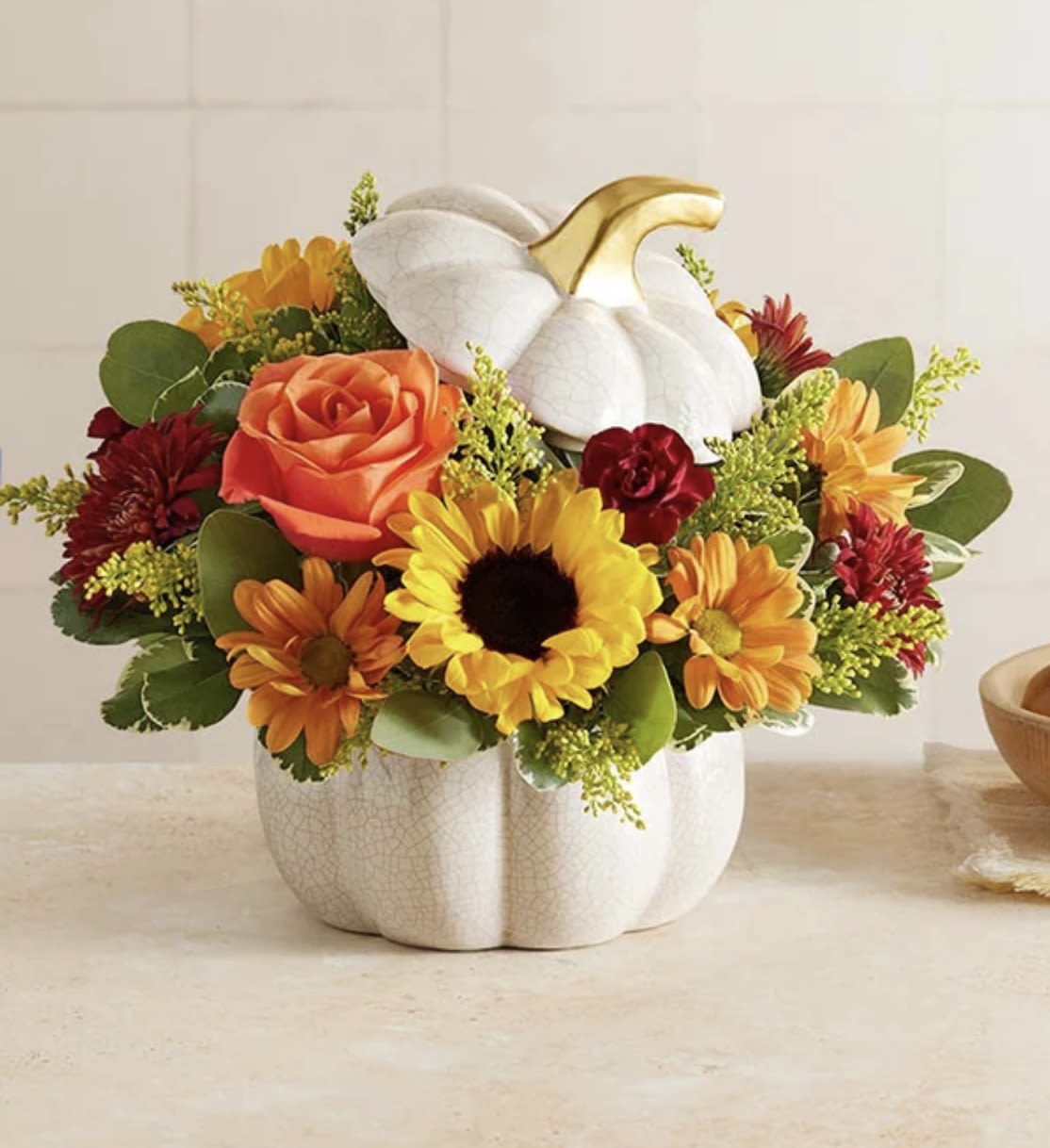 Fall arrangement with sunflowers, orange rose and mums in a white ceramic pumpkin container