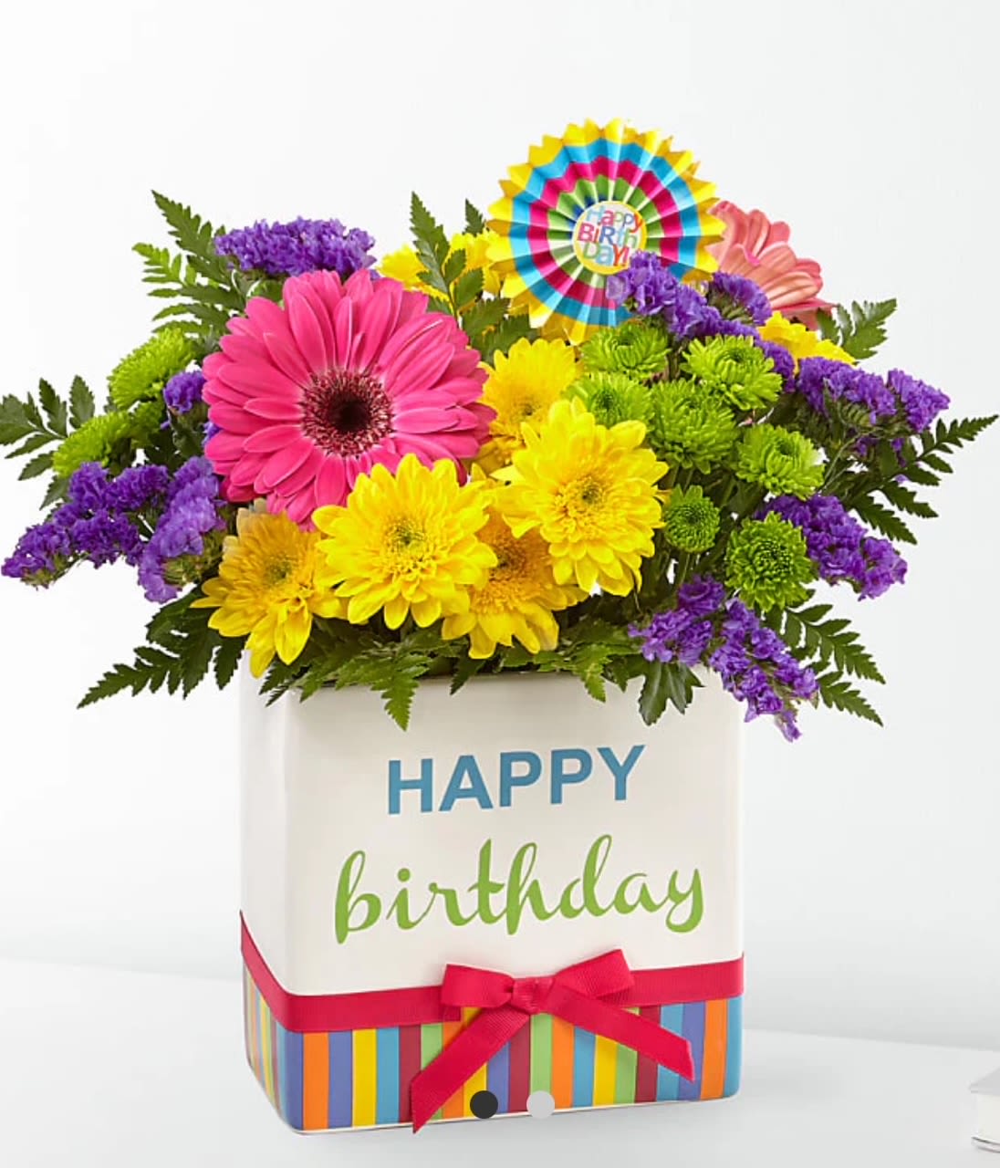 Bright birthday bouquet with pink gerbera, yellow blooms, and purple accents in a happy birthday cube vase
