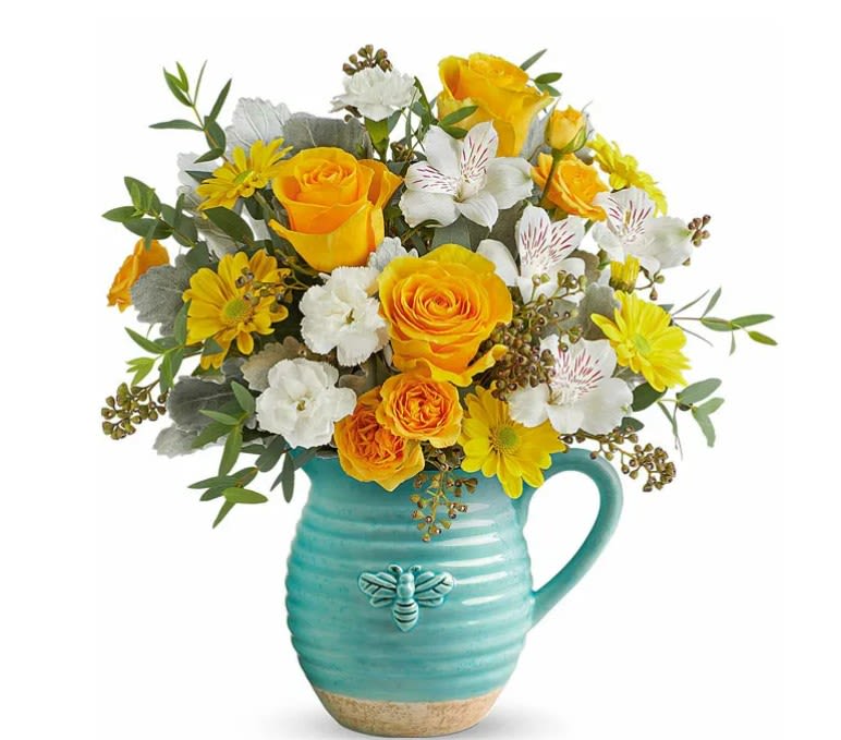 Yellow and white flower bouquet in a turquoise pitcher vase