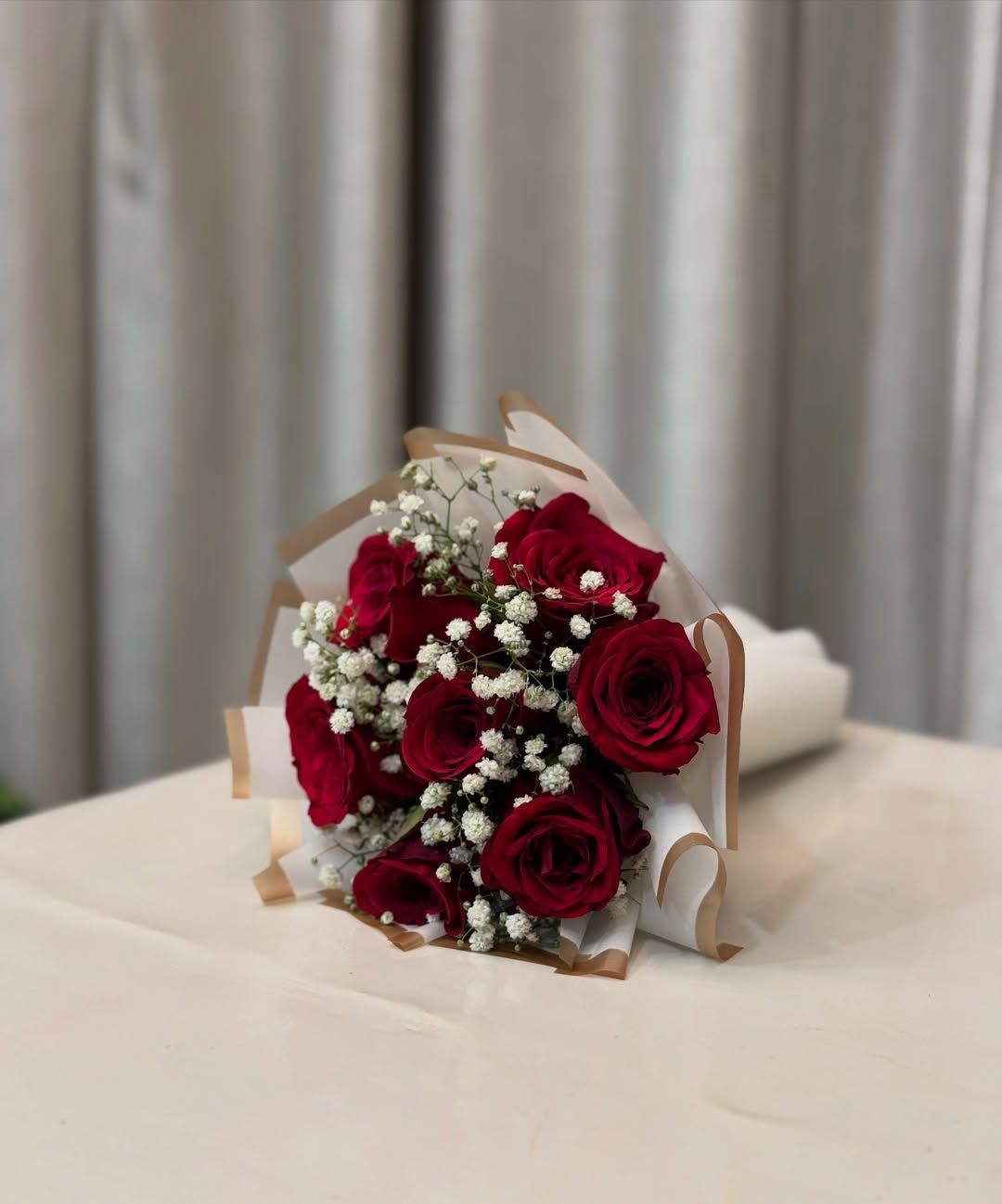Bouquet of red roses with white baby's breath in white and tan wrap