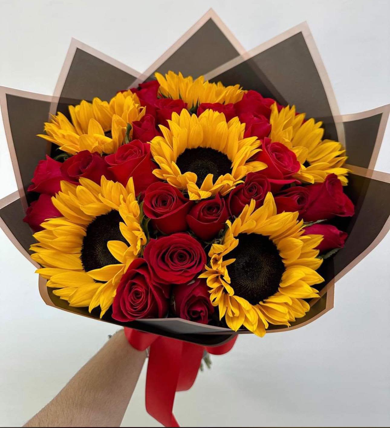 Bouquet of red roses and yellow sunflowers wrapped in dark paper