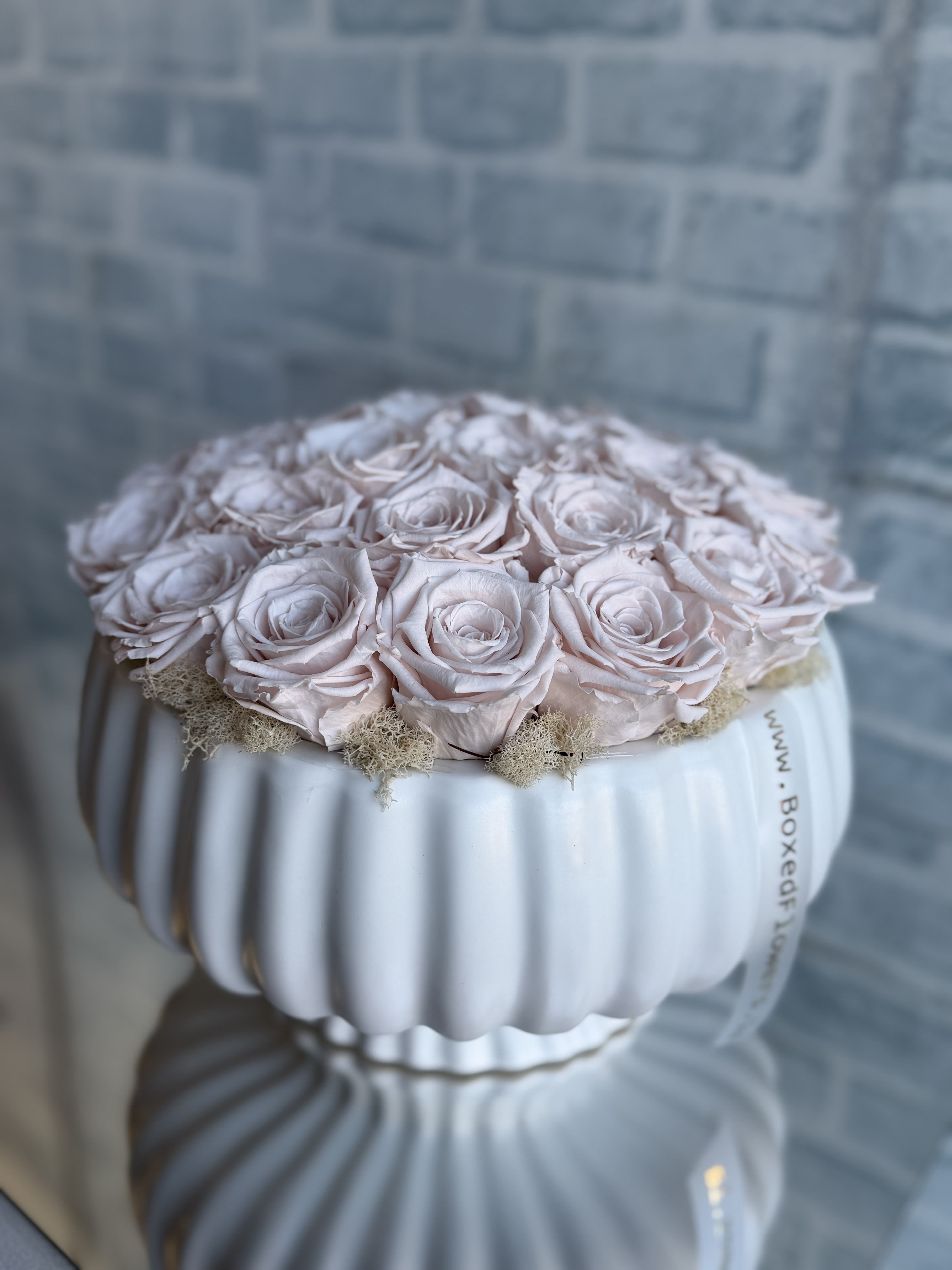 Pale pink roses arranged in a white ribbed vase