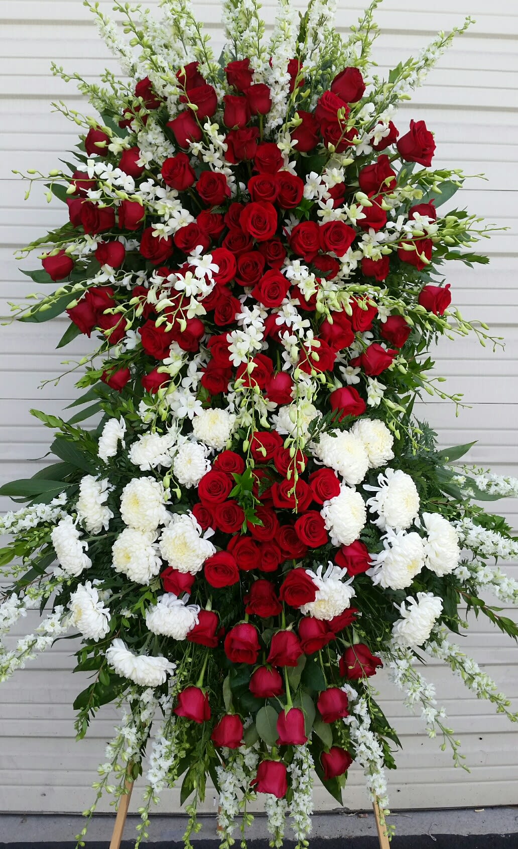 Large standing spray of red roses and white flowers on an easel