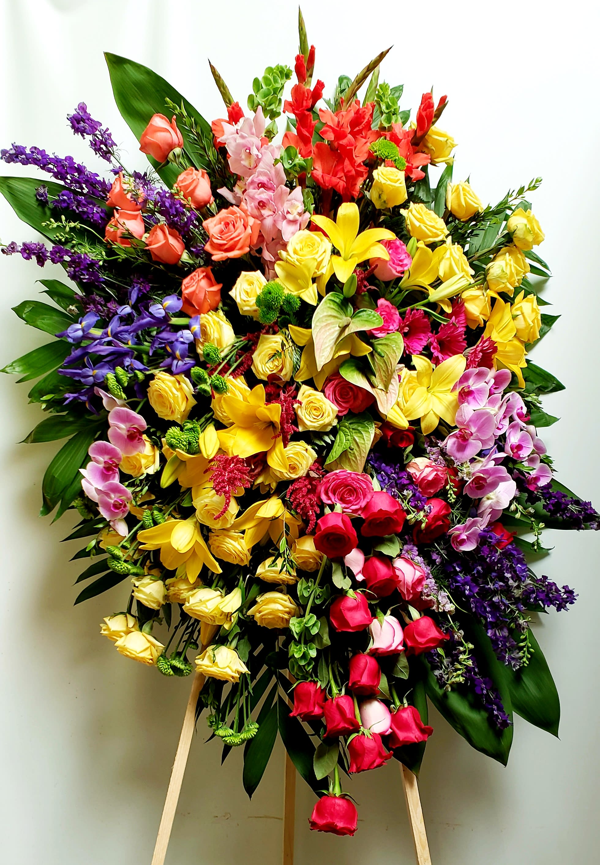 Large mixed floral standing spray with roses, lilies, orchids, and purple accents