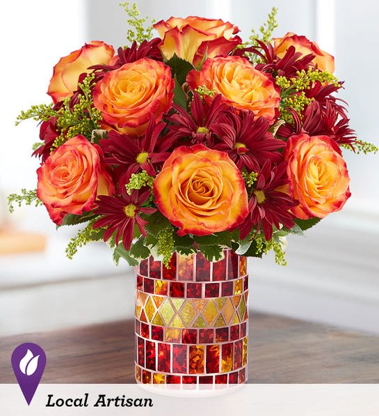 Orange roses and burgundy daisies in a mosaic glass vase
