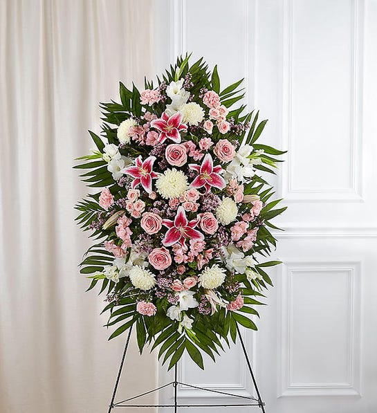 Standing floral spray with pink roses, lilies, and white blooms on an easel